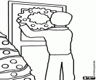 L'homme en accrochant la couronne de Noël dans la porte de sa maison